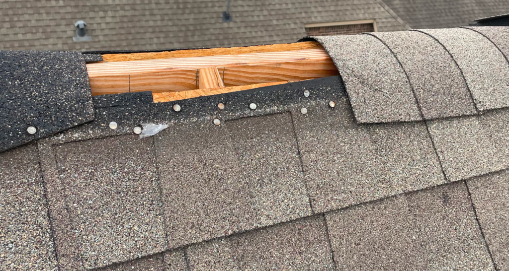 Damaged shingle roof being repaired.