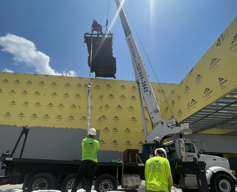 Crane installing roof materials.